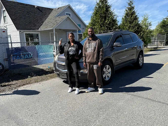 Two people standing next to SUV in residential neighborhood with house