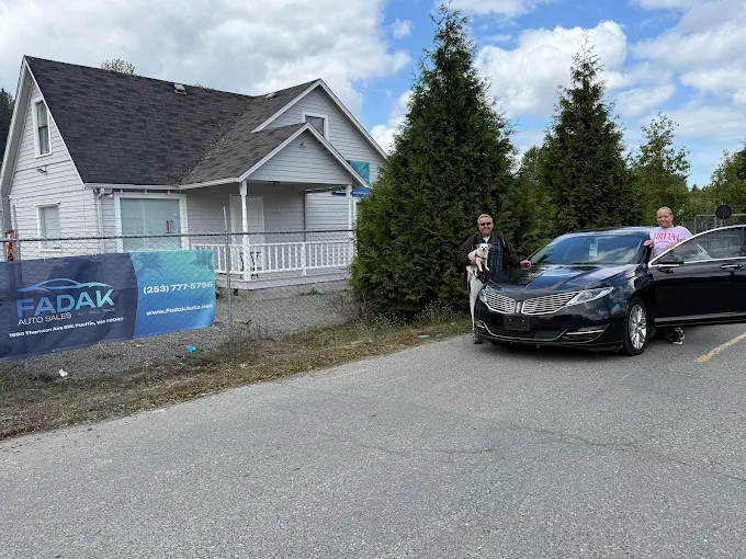 Black car parked near white house with Padak Auto Sales banner