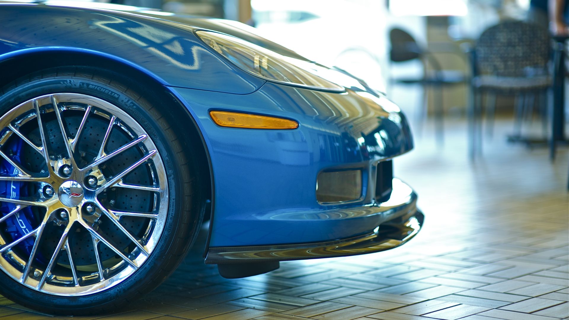 Blue Corvette with shiny chrome wheel in sleek showroom setting