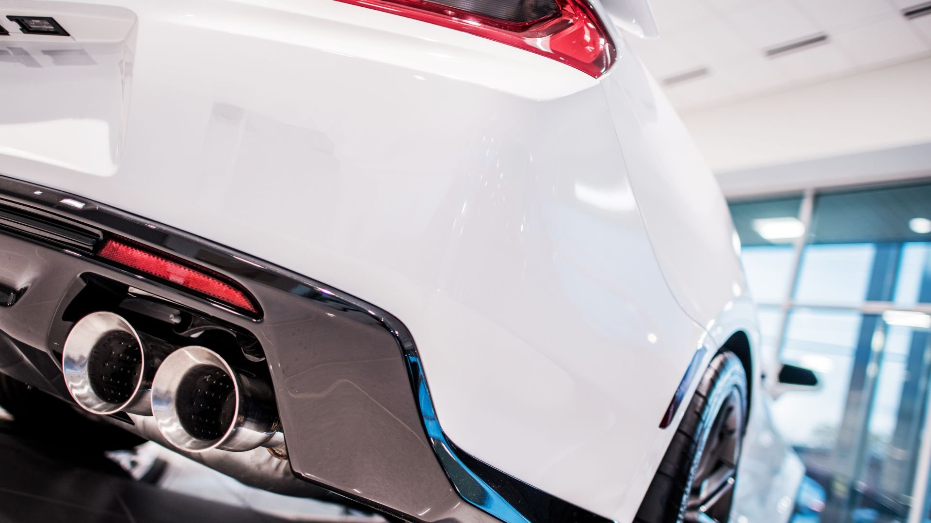 Close-up of white sports car with dual exhaust pipes in showroom